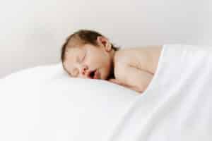 newborn baby boy sleeping on beanbag under a blanket.