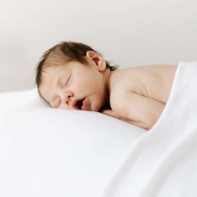 newborn baby boy sleeping on beanbag under a blanket.