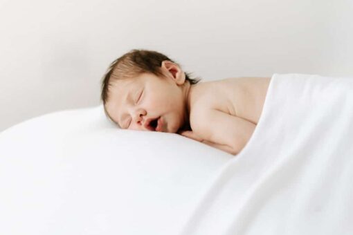 newborn baby boy sleeping on beanbag under a blanket.