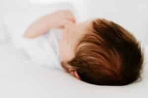 newborn baby boy on white beanbag during photoshoot.